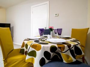 a dining room table with yellow chairs and purple glasses at Pass the Keys Spacious Well Equipped Flat in Gosforth