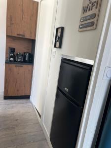 a kitchen with a black refrigerator in a hallway at Le Terminus in Aix-les-Bains