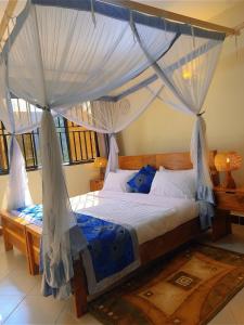 a bedroom with a canopy bed with mosquito nets at Airportlinkguesthouse2 in Entebbe