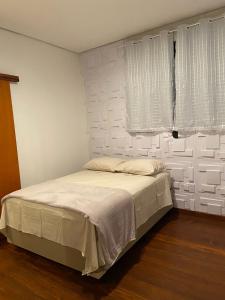 a bedroom with a bed with white walls and a window at Casa com ótima localização in São Sebastião