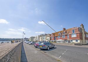 a street with cars parked on the side of a beach at Seaspray in Seaton