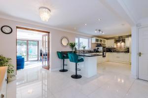 a kitchen with a counter and two green chairs at 5 bed detached - Worsley, Manchester in Worsley