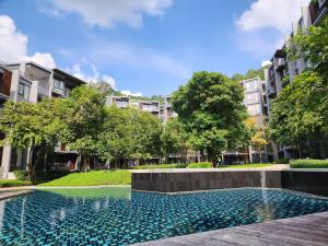 una piscina en medio de un patio con edificios en Mountain View Suite at The Valley Khaoyai, en Ban Huai Sok Noi