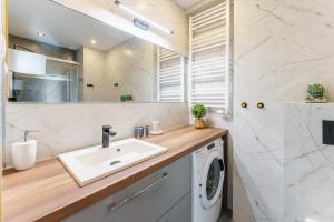 a bathroom with a sink and a washing machine at Apartament Emerald z Basenem Letnim by HolidaySun in Sianozety
