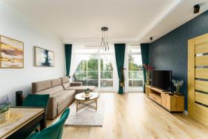 a living room with a couch and a tv at Apartament Emerald z Basenem Letnim by HolidaySun in Sianozety +29 photos
