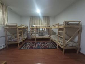a room with three bunk beds and a rug at KGB Home Hostel in Bishkek