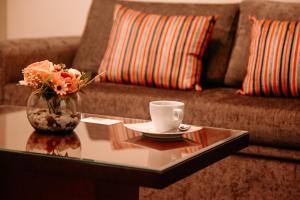 a coffee table with a vase of flowers and a cup of coffee at Hotel Carrera in Lima
