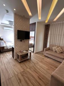 a living room with a couch and a flat screen tv at AlQimah Hotel Apartments in Amman