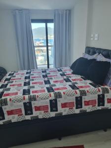 Una cama con un edredón rojo blanco y azul. en Frente mar 3 quartos Praia dos Anjos Residence, en Arraial do Cabo
