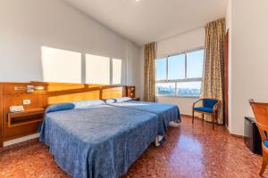 a hotel room with a bed and a desk and window at Port Europa in Calpe