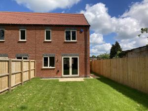 a brick house with a fence and a yard at Newly built 3 Bed house with ample parking 1 in Balderton