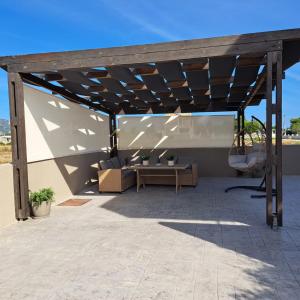 pérgola de madera con sofá y mesa en el patio en La Casa De Zante en Laganas