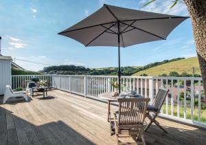 a patio with a table and an umbrella on a deck at The Lookout @ Highdown in Braunton