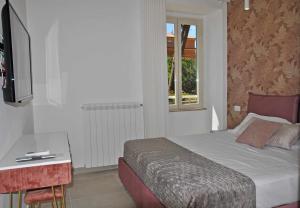 Schlafzimmer mit einem Bett, einem Schreibtisch und einem TV in der Unterkunft Brezza di mare appartamento fronte spiaggia in Formia