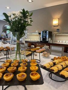 una mesa con varios pasteles y un jarrón de flores en Eurostars Oporto, en Oporto