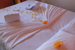 Una cama blanca con flores y una muñeca. en Papagaio Hostel & Pousada, en Morro de São Paulo
