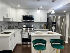 a kitchen with white cabinets and green bar stools at Tosam Luxury Lodge Two Bedroom Suite in Brampton