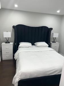 a bedroom with a large bed with white sheets and two lamps at Tosam Luxury Lodge Two Bedroom Suite in Brampton