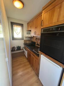 a kitchen with wooden cabinets and a sink and a dishwasher at Studio avec magnifique vue montagne - Praloup 1500 in Uvernet-Fours +6 photos