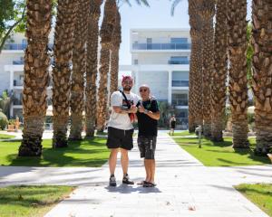 deux hommes debout sur un trottoir à côté des palmiers dans l'établissement FishaRent Luxury Royal Park Suites, à Eilat