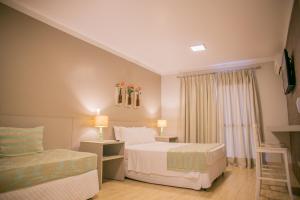 um quarto de hotel com uma cama e um sofá em Pousada Villa Di Enzo em Ubatuba