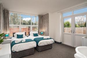 a bedroom with two beds and a large window at OYO Wilson Lodge in Maidenhead