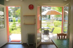 una puerta abierta a un patio con mesa y sombrilla en Appart'confort 4 personnes en Grandson