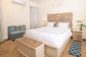 a bedroom with a large white bed and a chair at Sashas Holiday Village in Vagator