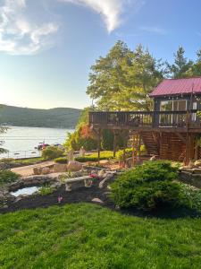 a house with a deck and a lake in the background at Cozy Lakeside Fall Escape; Applepick, Hike, Winery in Greenwood Lake