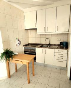 a kitchen with white cabinets and a wooden table at OceanView Side in Quarteira
