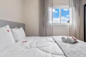 uma cama branca com toalhas e uma janela em VISTA 161 Apto em Gramado com vista espetacular em Gramado