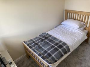 a small bed with a plaid blanket on it at Newly built 3 Bed House with Ample Parking 2 in Balderton