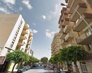 een straat met hoge gebouwen en een straat met auto's bij Buona Onda in Marsala