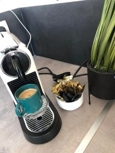 uma cafeteira com uma chávena de café ao lado de uma planta em Kasaloc em Maintenon