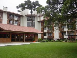 un grande edificio con un prato verde di fronte di Apartamento Pousada do Serrano a Gramado