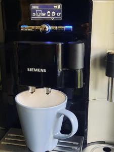 Lennuki Apartement في راكفيري: آلة صنع القهوة مع كوب قهوة أبيض على منضدة