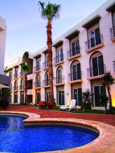 una palmera frente a un edificio con piscina en Seven Crown Express & Suites by Kavia en Cabo San Lucas