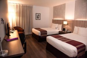 a hotel room with two beds and a desk at Aku Hotels in Lima