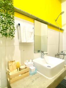La salle de bains est pourvue d'un lavabo blanc et d'un mur jaune. dans l'établissement Tiny Homes- Vintage Apartments, à Hanoï