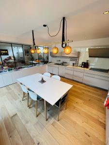 - une cuisine avec une table et des chaises blanches dans l'établissement LOFT Triplex 300m² à 10 min PARIS/EXPO, à Malakoff