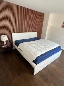 - un lit blanc dans une chambre dotée d'un mur en bois dans l'établissement LOFT Triplex 300m² à 10 min PARIS/EXPO, à Malakoff