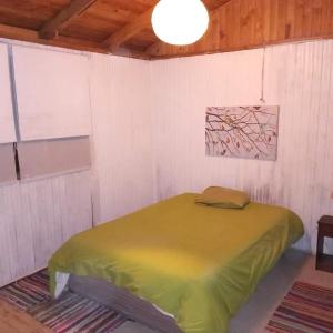 1 dormitorio con 1 cama verde en una pared blanca en CASA kuntur en Cajon del Maipo