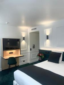 - une chambre avec un lit, une télévision et un bureau dans l'établissement Maison Philippe Le Bon, à Dijon