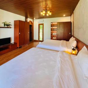 a large white bed in a room with a tv at Vườn Trà HomeStay Măng Đen in Kon Von Kla