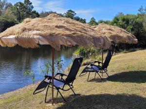 two chairs under a straw umbrella next to the water at steve and cori's tropical king suite 2 in North Port