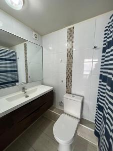 a bathroom with a toilet and a sink and a mirror at Lindo departamento al borde de la playa in Iquique