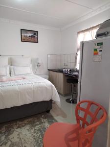 a bedroom with a bed and a red chair at 4 Centenary Road Ixopo in Ixopo