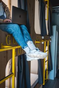 a person sitting on a bunk bed with a laptop at Capsule Hostel Logistic Vilnius in Vilnius