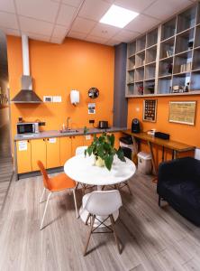 una oficina con paredes de color naranja y una mesa y sillas blancas en Capsule Hostel Logistic Vilnius en Vilna