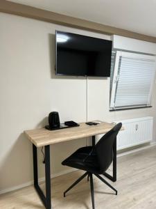 a desk with a chair and a television on a wall at Rheinischer Hof Appartements in Leverkusen